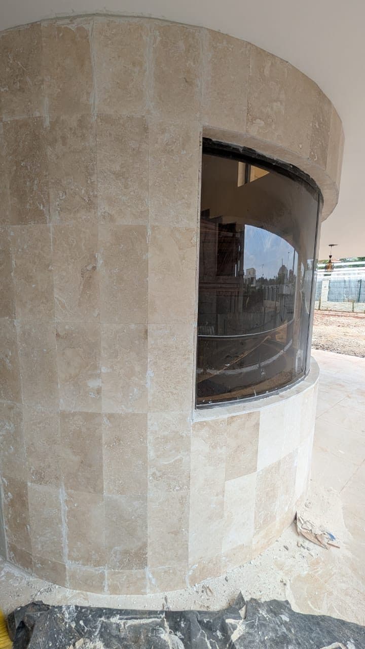 Detail: hand-set travertine coursing around a curved glass bay window - built by Royalwoods Interiors, Nairobi