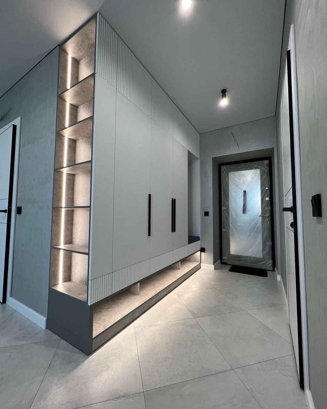 Fluted hallway storage unit with LED-lit niche beside the entrance door - bespoke joinery by Royalwoods Interiors, Nairobi