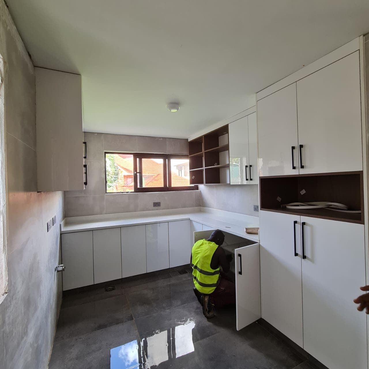 Our fitter aligning base units during a white gloss kitchen installation - bespoke joinery by Royalwoods Interiors, Nairobi