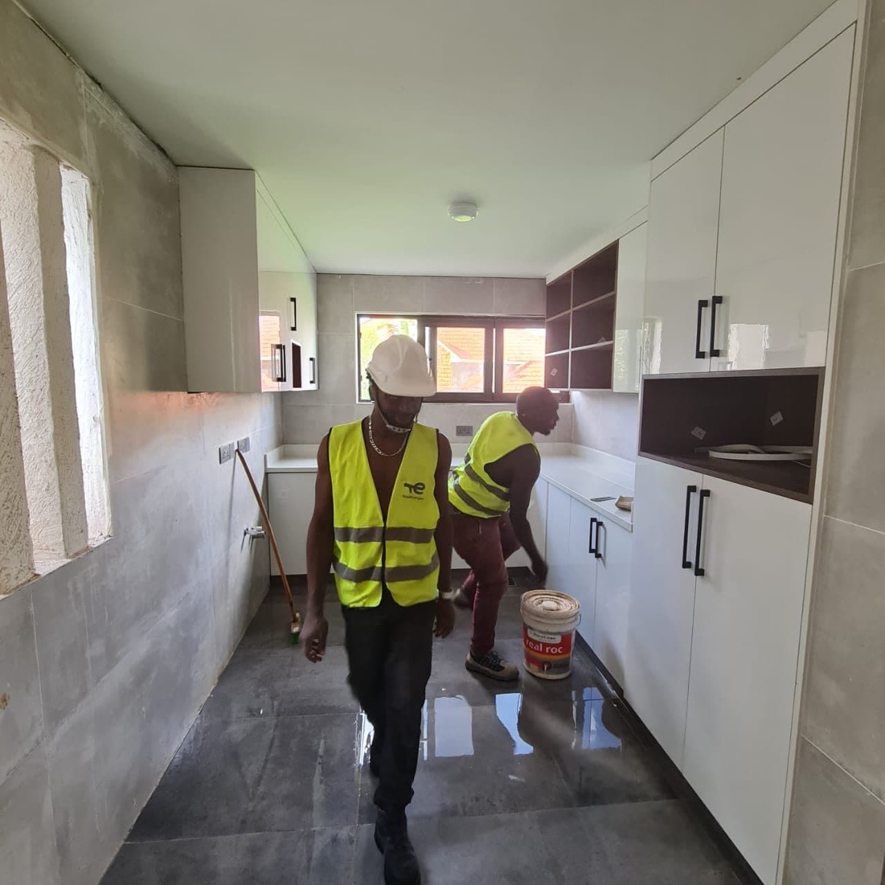 Installation team moving materials through a kitchen mid-fit-out - bespoke joinery by Royalwoods Interiors, Nairobi