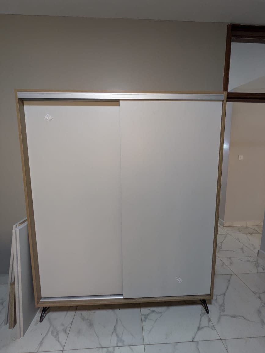 Sliding-door shoe cabinet closed - clean two-panel face on hairpin feet - bespoke joinery by Royalwoods Interiors, Nairobi