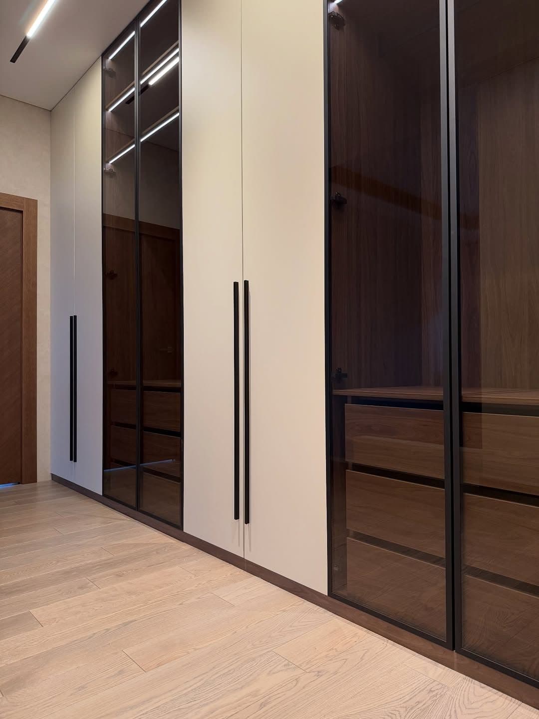 Bronze-glass wardrobe run viewed from the bedroom corridor - bespoke joinery by Royalwoods Interiors, Nairobi