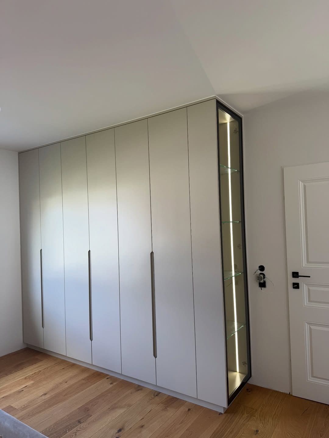 Floor-to-ceiling wardrobe with LED-lit glass display column beside the bedroom door - bespoke joinery by Royalwoods Interiors, Nairobi