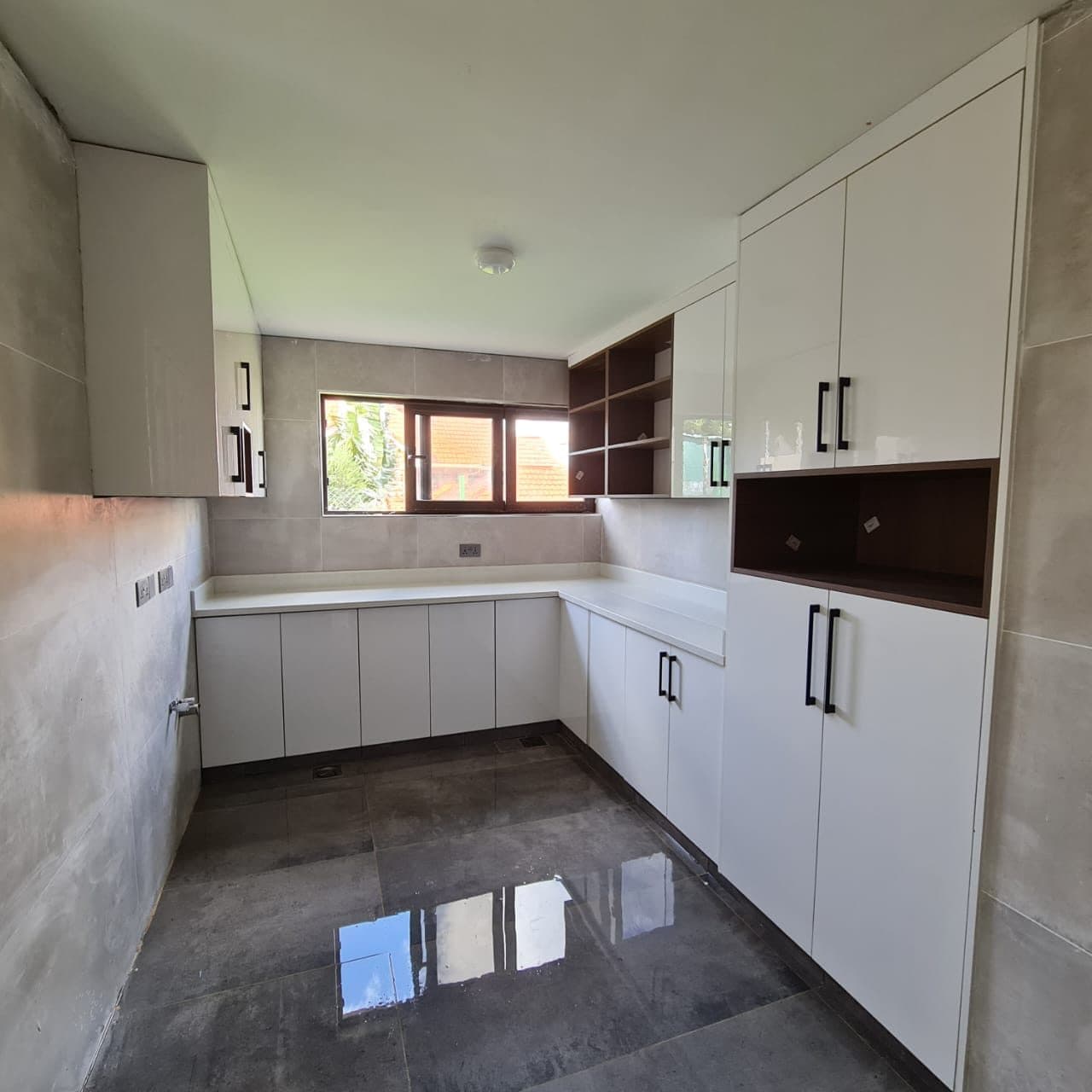 White gloss U-shaped kitchen with dark honed-porcelain floor, awaiting appliances - bespoke joinery by Royalwoods Interiors, Nairobi