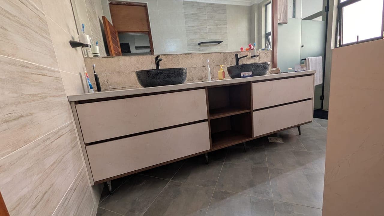Corner view — the vanity floats clear of the floor on slim tapered legs - bespoke joinery by Royalwoods Interiors, Nairobi