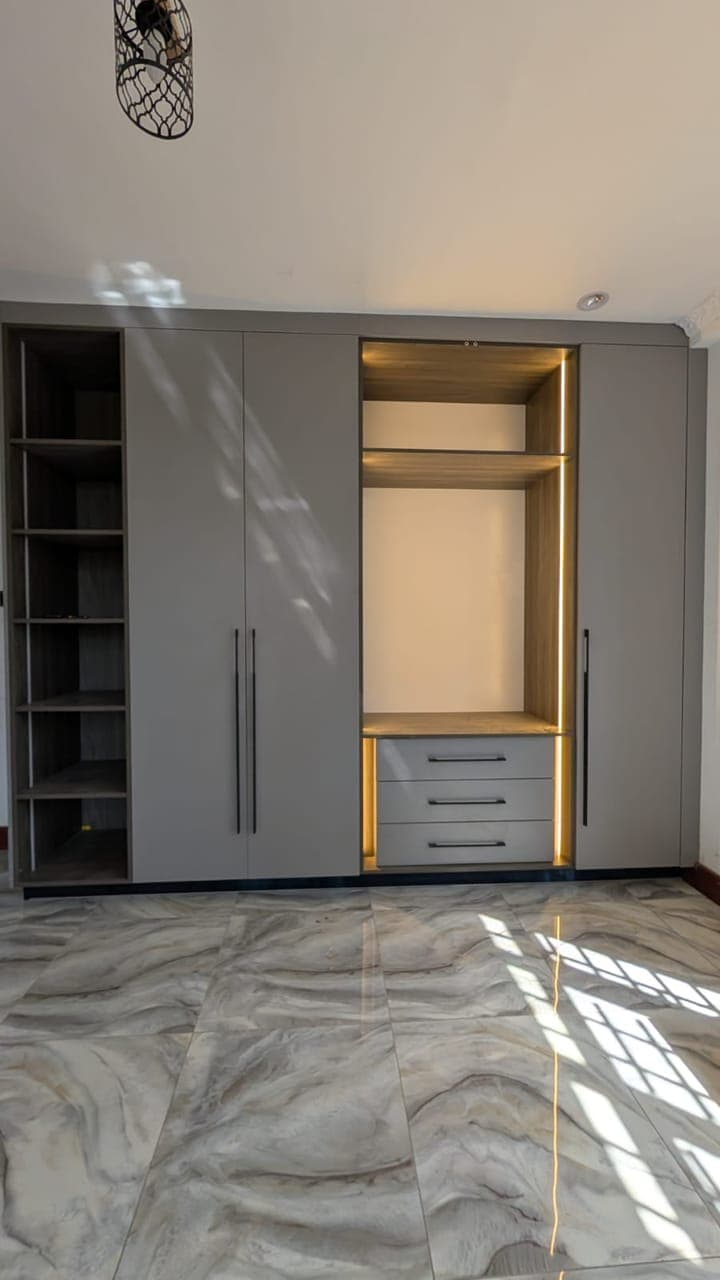 Gold-trimmed drawers below a double-height hanging section - bespoke joinery by Royalwoods Interiors, Nairobi