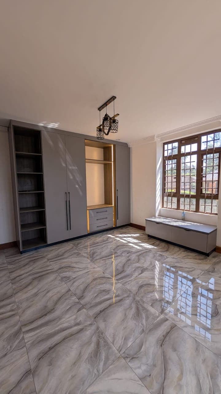 The wardrobe wall from the bed — hanging, shelving and a reading bench - bespoke joinery by Royalwoods Interiors, Nairobi