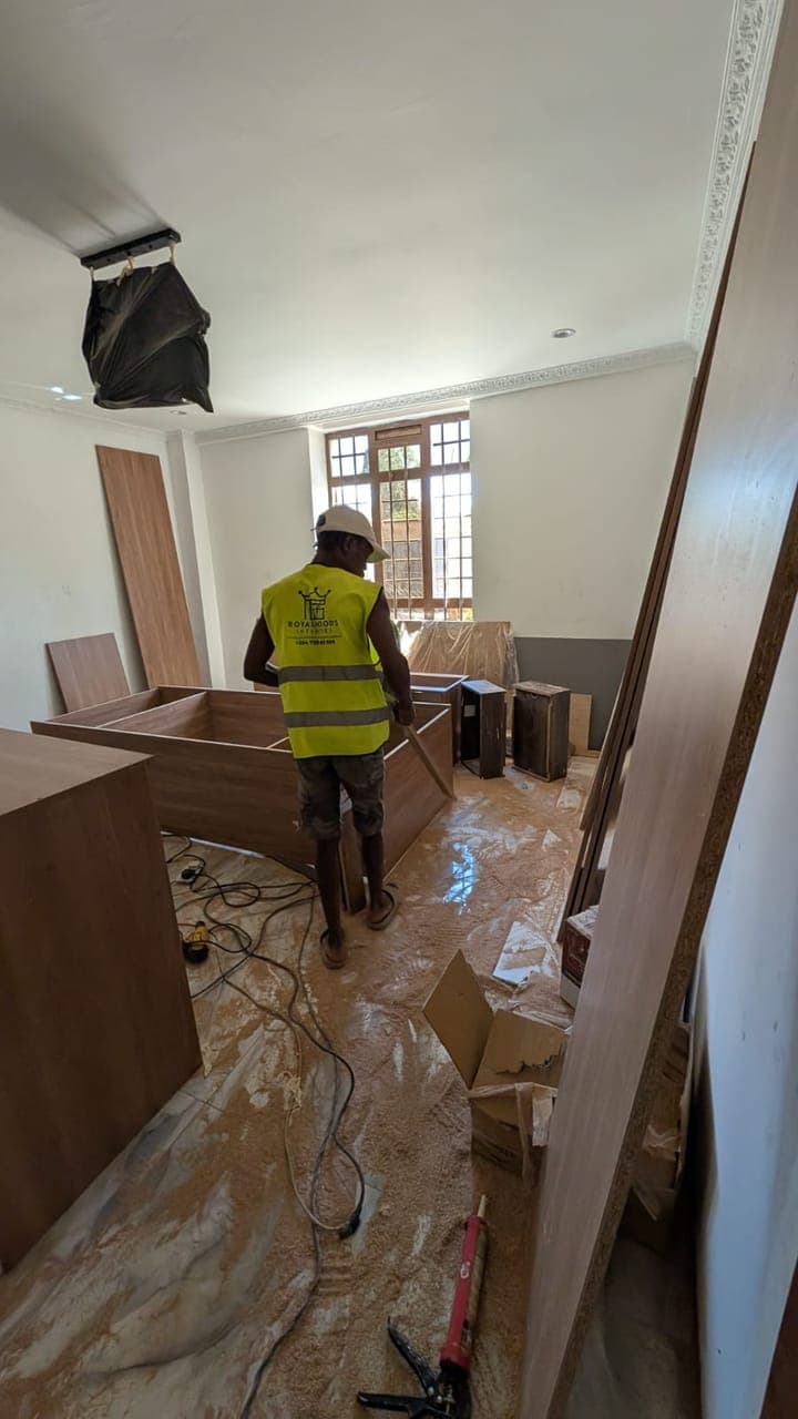Island carcass in place, tall glazing beyond — the kitchen mid-installation - bespoke joinery by Royalwoods Interiors, Nairobi