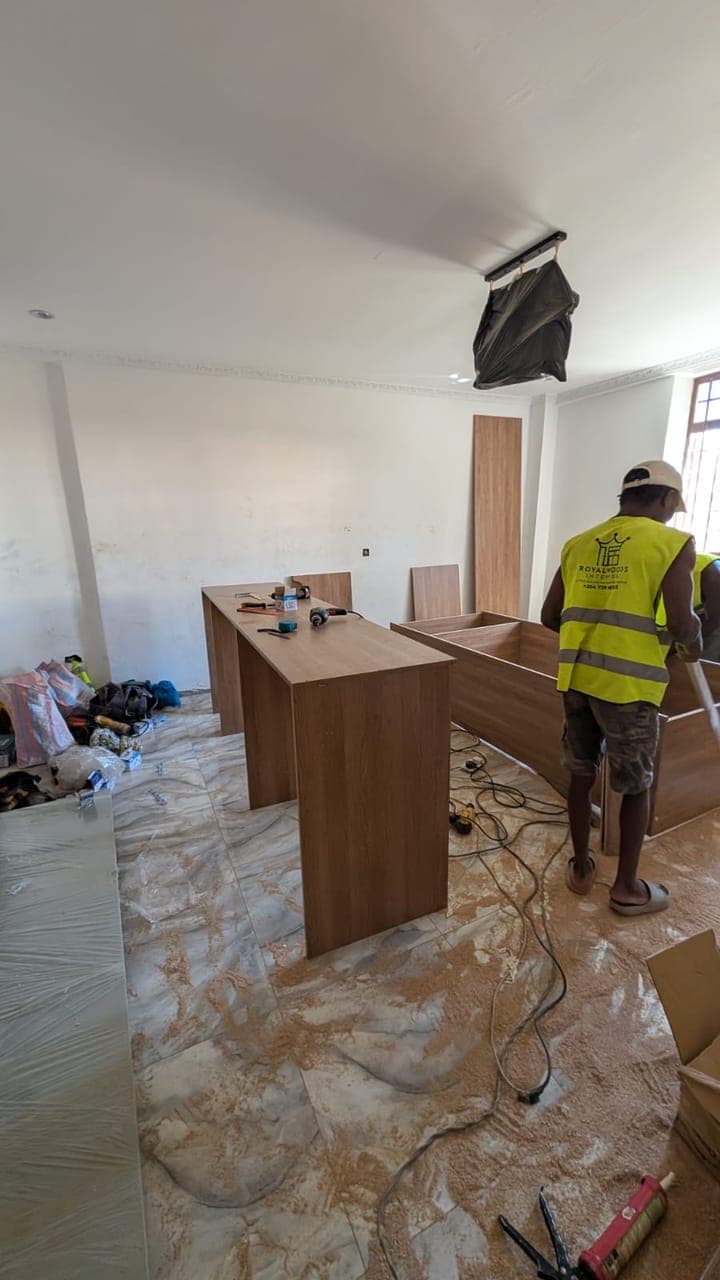 Fitting a timber kitchen island over polished onyx-look floors, still under dust sheets - bespoke joinery by Royalwoods Interiors, Nairobi
