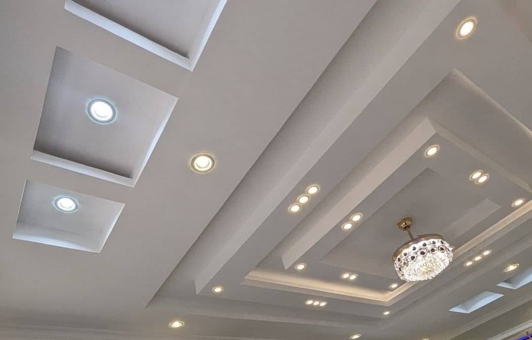 Layered gypsum tray ceiling with recessed spotlights and a crystal chandelier - Royalwoods Interiors, Nairobi