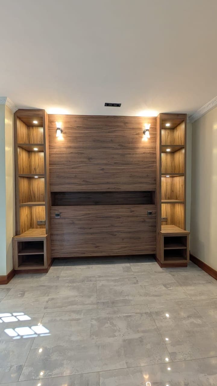 Warm timber and bronze-tinted glass, lit for the evening - bespoke joinery by Royalwoods Interiors, Nairobi