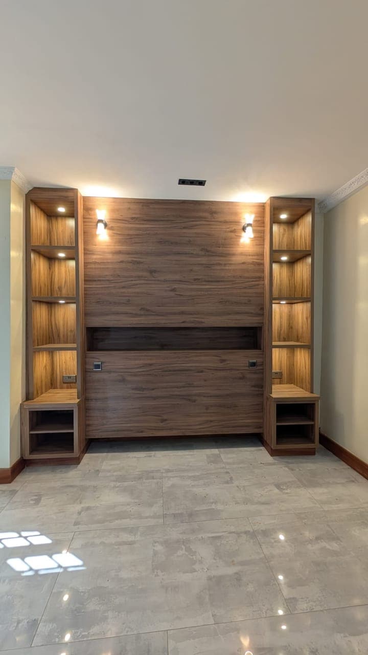 Walnut media wall — glass display towers lit from within above a floating shelf - bespoke joinery by Royalwoods Interiors, Nairobi