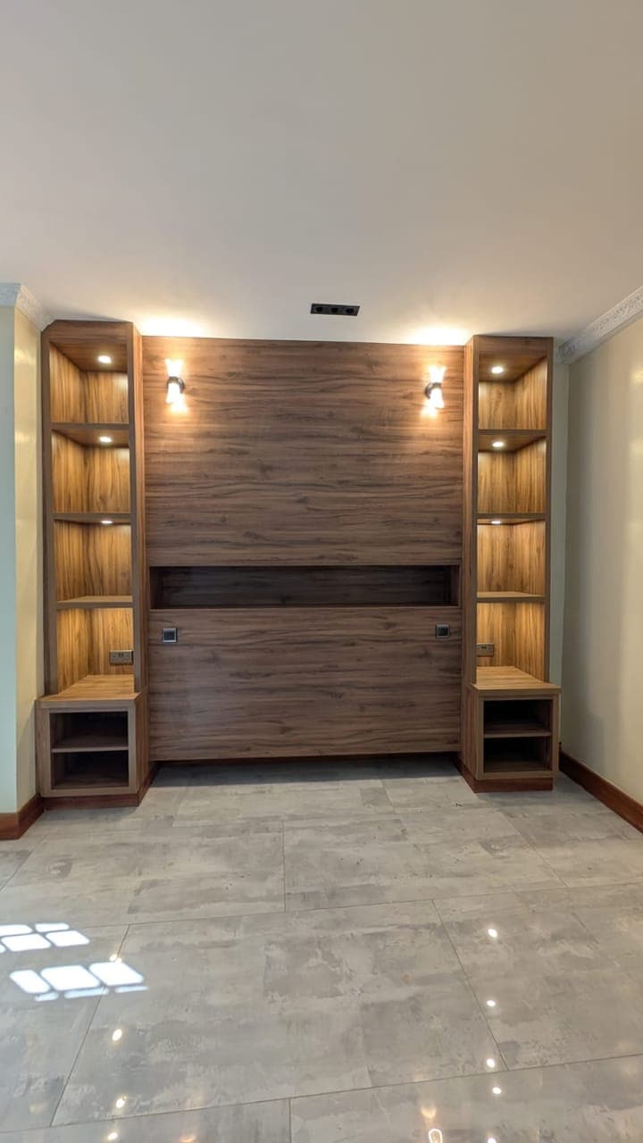 Open cubbies and lit display towers flank the screen recess - bespoke joinery by Royalwoods Interiors, Nairobi
