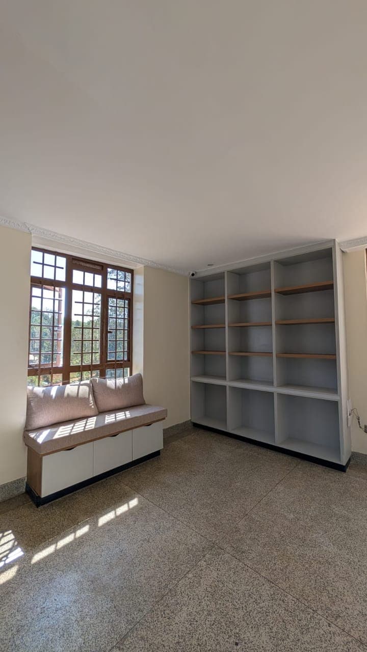 Built-in white shelving beside a cushioned window bench, on terrazzo - bespoke joinery by Royalwoods Interiors, Nairobi