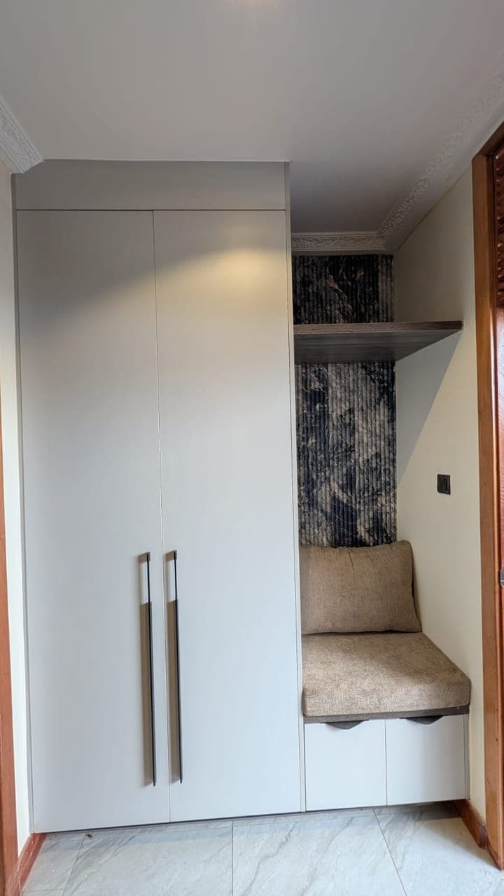 Wardrobe bank with a marble feature panel and an upholstered dressing bench - bespoke joinery by Royalwoods Interiors, Nairobi