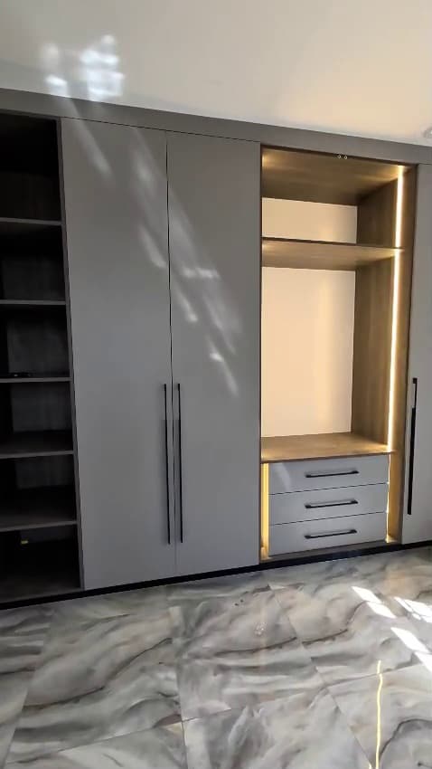 Grey bedroom wardrobe with gold-edged drawers and a fluted timber panel — Royalwoods Interiors, Nairobi