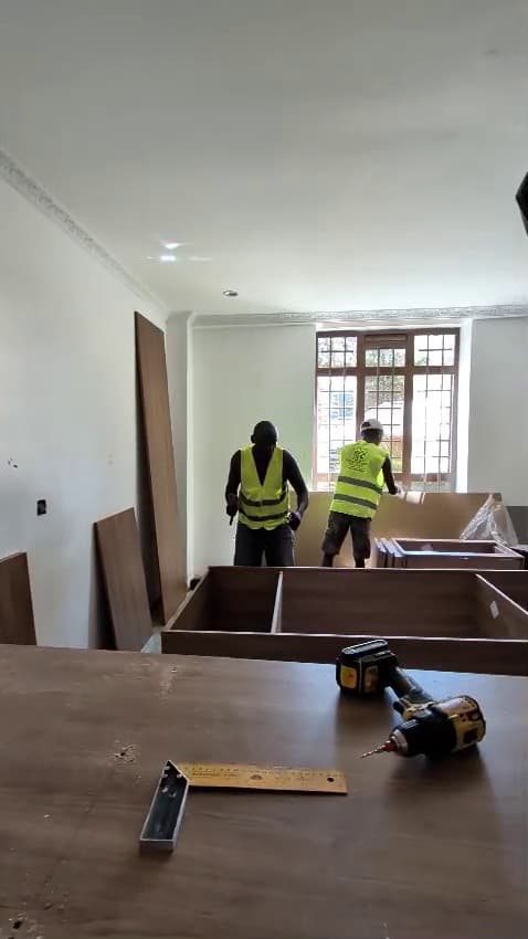 A Royalwoods craftsman fitting a timber kitchen island on site — Royalwoods Interiors, Nairobi