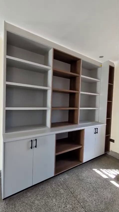 Built-in white display shelving beside a window bench in a bright living room — Royalwoods Interiors, Nairobi