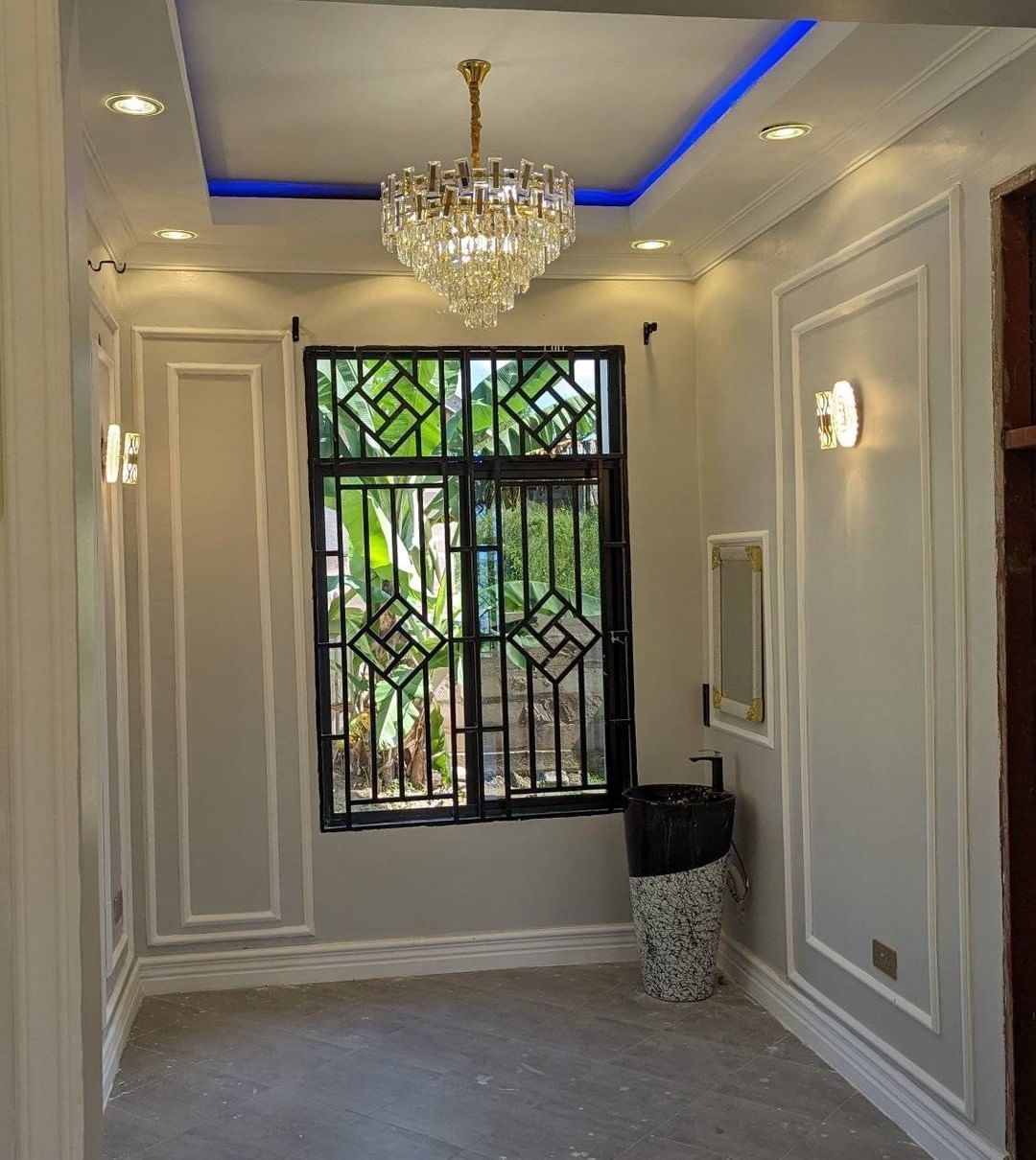 Classical wall panelling and crystal chandelier in a Runda living room by Royalwoods Interiors
