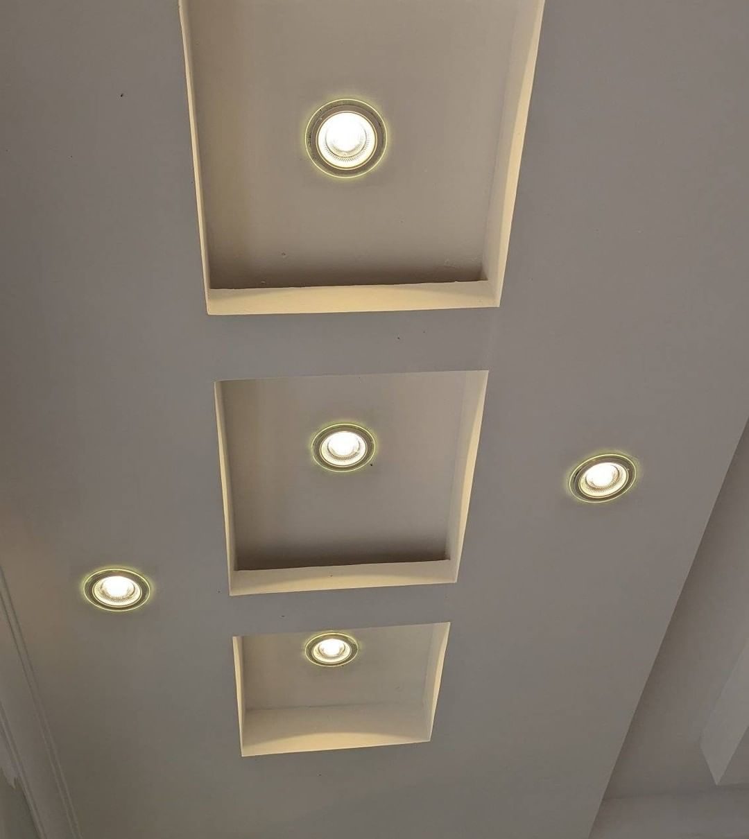 Stepped gypsum ceiling recesses with warm recessed lighting in an executive lounge by Royalwoods Interiors