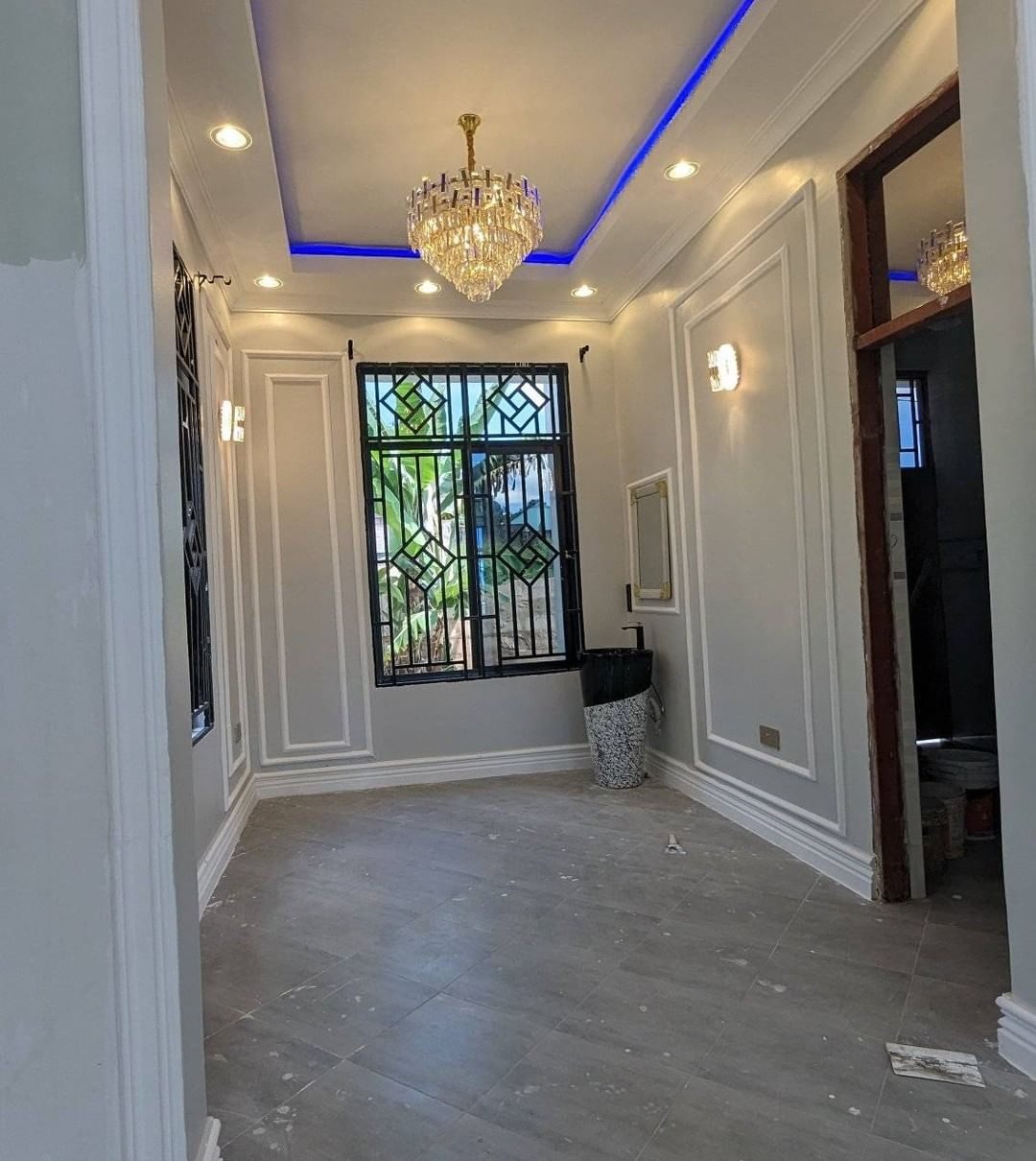 Panelled reception room beneath an LED cove ceiling and chandelier by Royalwoods Interiors